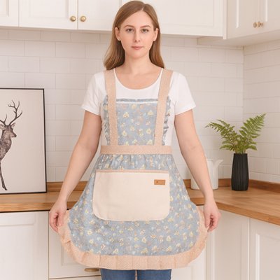 femme-portant-tablier-bleu-clair-avec-moifs-fleurs-pose-debout-dans-cuisine