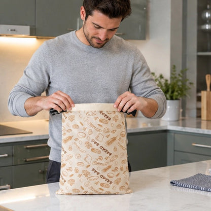 un-homme-souriant-vetu-dun-pull-gris-clair-ouvre-un-sac-a-pain-beige-decorer-de-motifs-de-boulangerie-dorer-poser-sur-le-comptoir-dune-cuisine-moderne-et-elegante