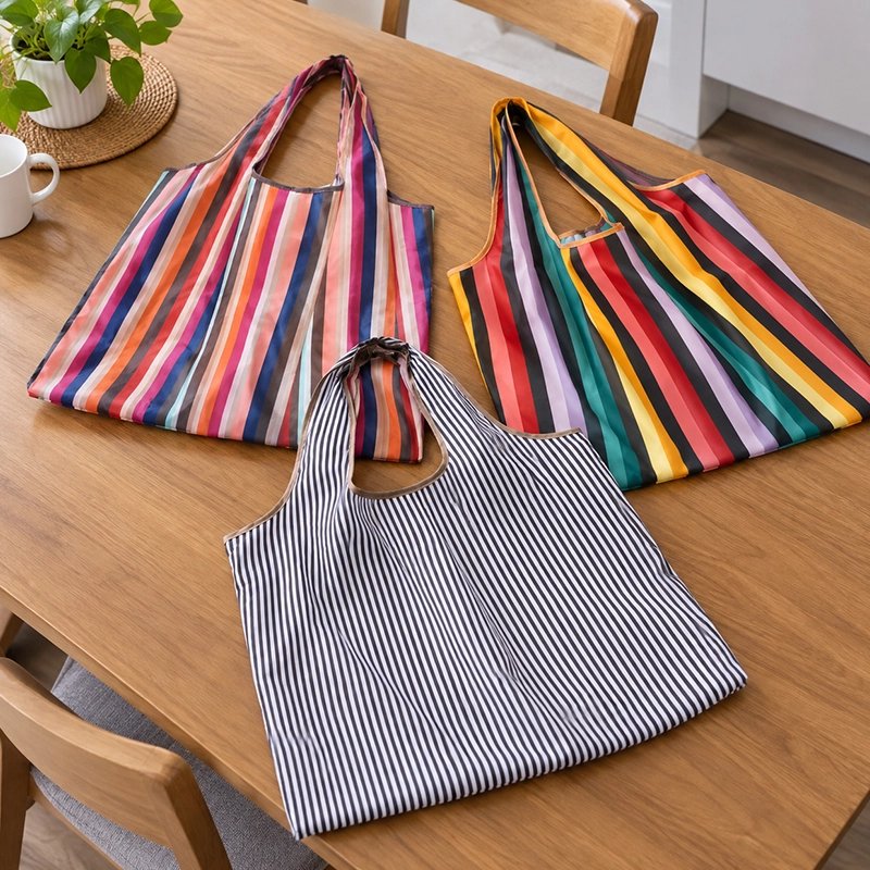 trois-sacs-de-courses-reutilisables-sont-poser-sur-une-table-en-bois-le-premier-presente-des-rayures-multicolores-aux-tons-roses-et-oranger-le-deuxieme-des-raures-vives=rouges-jaunes-vertes-blanches-tous-possedent-de-larges-anses-assorties