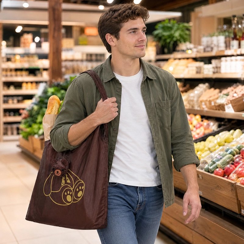 jeune-homme-vetu-dune-chemise-verte-et-jeans-bleu-marche-dans-super-marcher-porte-sur-lepaule-un-grand-sac-de-courses-reutilisable-marron-decorer-dun-ours-en-peluche-dorer-avec-une-baguette-de-pain-qui-depasse