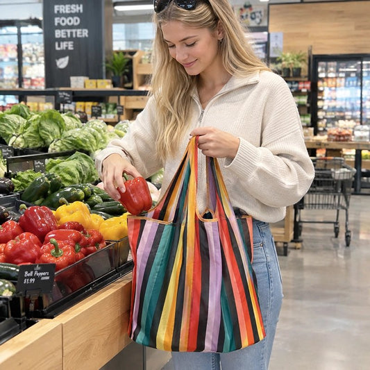 une-jeune-femme-blonde-souriante-vetue-dun-pull-blanc-et-dun-jean-bleu-glisse-un-poivron-rouge-dans-un-grand-sac-reutilisable-a-rayures-verticales-multicolores-dans-le-rayon-legumes-dun-supermarcher