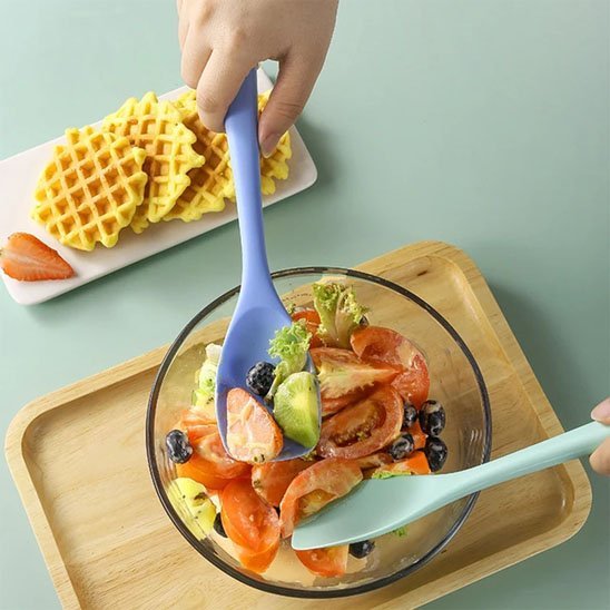 spatule en silicone mauve melangeant salade