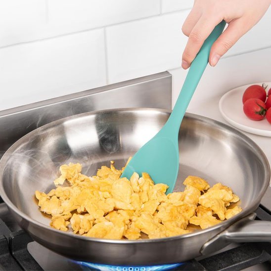 spatule en silicone verte dans un poele sur le feu